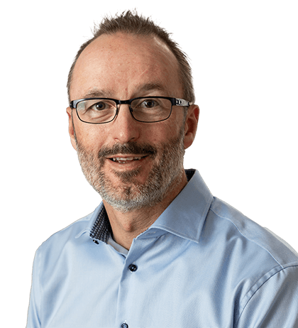A man with short brown hair, glasses, and a beard wearing a light blue collared shirt, smiling at the camera.
