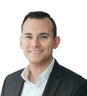 Georges Nasr, a man with short dark hair, is seen wearing a dark patterned blazer and white shirt, smiling at the camera against a plain background.