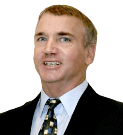 Howard Haskings, a man in a suit and patterned tie, is facing forward and smiling, with short light brown hair and a light skin tone against a plain background.