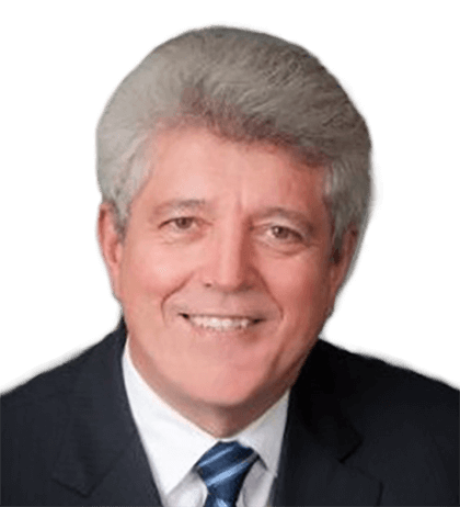 Jacques Beaudoin, a middle-aged man with gray hair, wears a dark suit, white shirt, and striped tie as he smiles warmly at the camera.