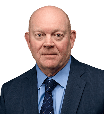 Wayne Wiggins, a bald man in a blue suit, blue shirt, and patterned tie, poses for a professional headshot against a plain background.