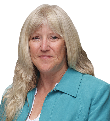 Gerry Barton, a woman with long blonde hair, wearing a teal jacket and white top, smiles slightly while facing the camera against a neutral background, embodying Gerry Bartons signature style.
